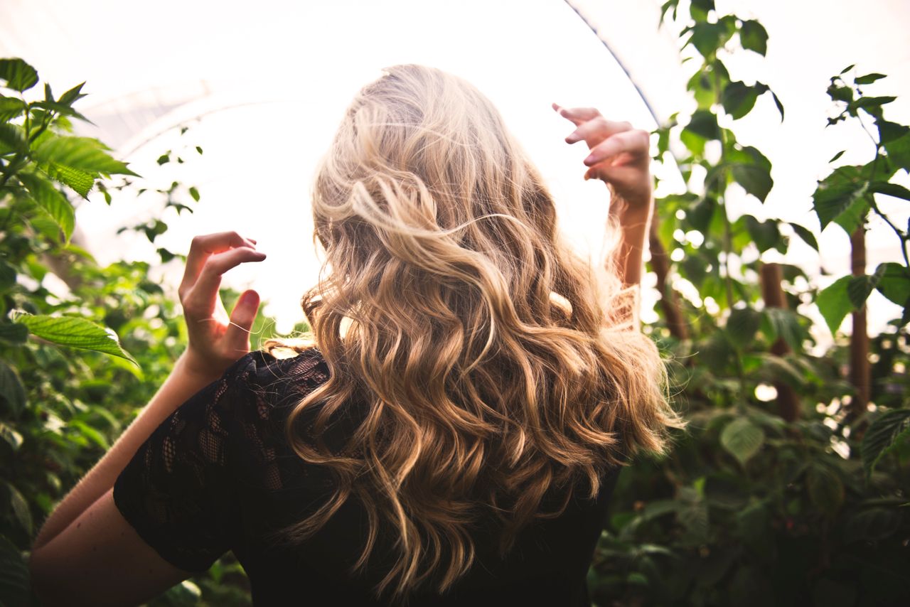 Mastering the First Impression: Your intriguing post title goes here Blonde woman with curly hair surrounded by lush greenery, enjoying a sunny day.