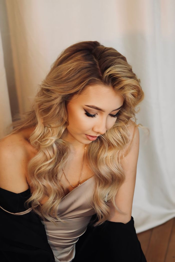 Contact Beautiful portrait of a blonde woman looking down in a satin dress against a white background.
